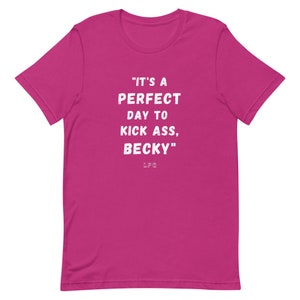 May include: A magenta-colored t-shirt with the phrase "IT'S A PERFECT DAY TO KICK ASS, BECKY" printed in white, along with the initials "LFG" below the text. The shirt has a crew neck and short sleeves.