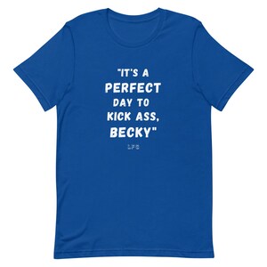 May include: Royal blue t-shirt with the white text: "IT'S A PERFECT DAY TO KICK ASS, BECKY." The initials "LFG" are below the text. The shirt is a short-sleeved crew neck.