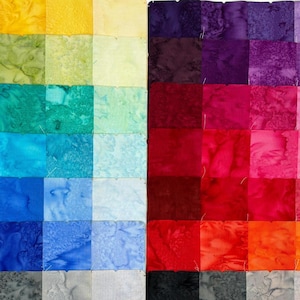 May include: A color gradient quilt made of fabric squares. The quilt is divided into two sections, each with a different color scheme. The left section features shades of blue, green, yellow, and orange. The right section features shades of purple, red, orange, and pink.