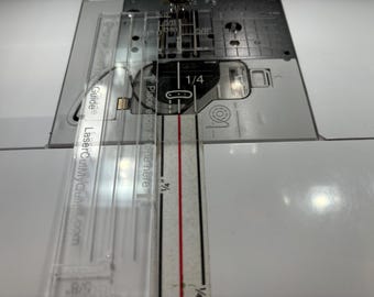 May include: A clear plastic sewing guide with the text "LaserCutMyCraft.com" and "Guide = Place edge here 1/4" printed on it. The guide is placed on a white sewing machine.