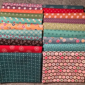 May include: A stack of 18 fabric squares with various patterns, including polka dots, floral prints, and geometric designs. The fabrics are in shades of teal, orange, red, brown, and gray.