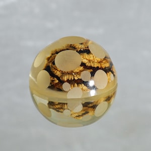 May include: A clear glass sphere containing a brown and gold floral design. The sphere is filled with white polka dots.