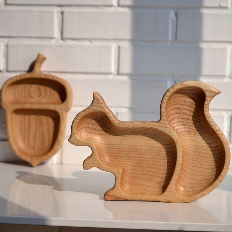 May include: Two wooden plates shaped like a squirrel and an acorn. The plates are made of light wood and have a natural finish.