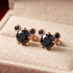 May include: A white ceramic mug with a black handle and the text "But First, Coffee" in a bold, black font. The mug is set against a blurred background, suggesting a cosy setting.