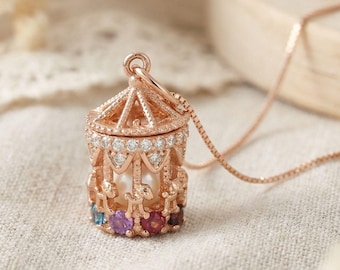 Pode incluir: Um pingente de carrossel em ouro rosa com uma pérola branca central, um telhado com detalhes metálicos complexos e uma base adornada com uma fileira de pequenas pedras preciosas redondas multicoloridas. A estrutura é realçada por pedras claras.