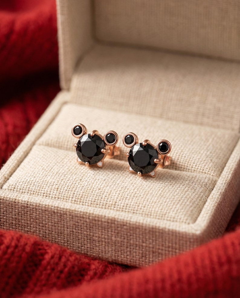 May include: A white ceramic mug with a black handle and the text "But First, Coffee" in a bold, black font. The mug is set against a blurred background, suggesting a cosy setting.