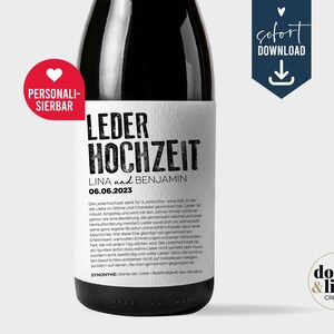 Peut inclure: Une bouteille en verre foncé avec une étiquette rectangulaire blanche portant le texte noir LEDER HOCHZEIT, LINA und BENJAMIN, et 06.06.2023. Un badge circulaire rouge avec un cœur blanc et le mot PERSONALISIERBAR est fixé en haut à gauche.