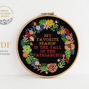 May include: A black and white cross stitch pattern with a floral wreath surrounding the text "My favorite season is the fall of the patriarchy".