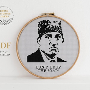 May include: Black and white cross stitch pattern of a man with a hat and the text "Don't drop the soap!"