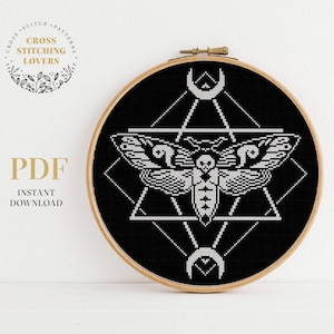 Può includere: Un motivo a punto croce in bianco e nero di una falena all'interno di forme geometriche, incorniciato in un telaio da ricamo in legno. Il design include una falena, triangoli e mezzelune. Il testo "PDF DOWNLOAD IMMEDIATO" è visibile.