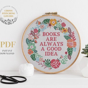 May include: A cross stitch pattern featuring a floral wreath with the text "Books are always a good idea".
