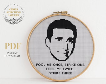 May include: A black and white cross stitch pattern featuring a portrait of a man with the text "Fool me once, strike one. Fool me twice... Strike three."