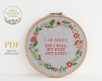 May include: A cross stitch pattern featuring a floral wreath with the text "I am sorry, did I roll my eyes out loud?" in red lettering.