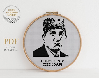 May include: Black and white cross stitch pattern of a man with a hat and the text "Don't drop the soap!"