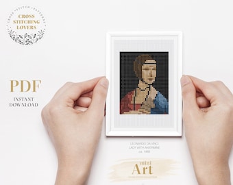 May include: A white frame with a cross stitch pattern of Leonardo da Vinci's Lady with an Ermine. The frame is held by hands against a white background. The text "PDF Instant Download" is below the frame. The text "mini Art Cross Stitch Collection" is below the image.