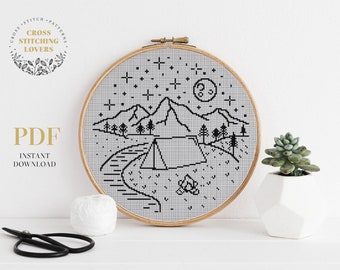 May include: Black and white cross stitch pattern of a mountain landscape with a tent, a campfire, a moon, and stars. The pattern is in a wooden embroidery hoop. The text "PDF INSTANT DOWNLOAD" is in the lower left corner.