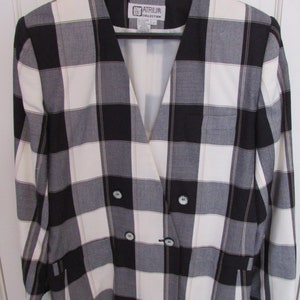 May include: A black and white plaid blazer with a double breasted closure and the label "Atrium Collection" on the inside.