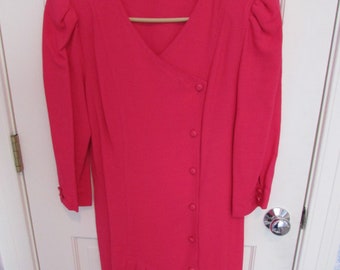 May include: A long-sleeved, pink dress with a V-neckline and a button-up front. The dress has a pleated skirt and puffed sleeves.