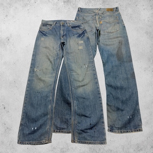 Könnte beinhalten: Zwei Paar hellblaue Jeans aus Denim mit Used-Look. Das vordere Paar hat einen Knopfverschluss, Vordertaschen und dezente Sitzfalten. Das hintere Paar zeigt Gesäßtaschen, einen Aufnäher in Lederoptik und sichtbare Farbspritzer-Details.