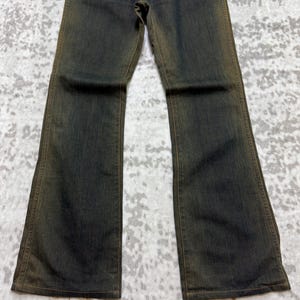May include: Dark wash denim jeans with a slight flare at the bottom. The jeans have a faded, worn appearance with subtle color variations. The fabric appears to be a medium weight, suitable for everyday wear.