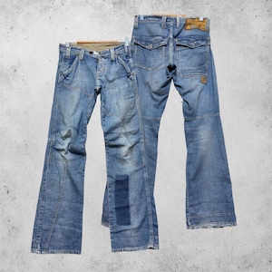 May include: Two pairs of light blue denim jeans with a faded wash. One pair shows the front with a button fly, belt loops, and a rectangular patch on the lower leg. The other pair shows the back with two flap pockets and a brown leather brand label.