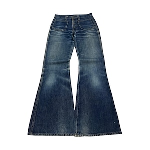 Puede incluir: Vaqueros azules de campana. Los vaqueros tienen bragueta con botones, dos bolsillos delanteros y dos traseros. El denim tiene un lavado descolorido con zonas más claras. Las campanas son anchas y acampanadas.