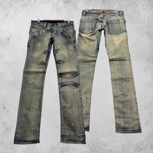 Könnte beinhalten: Zwei Paar hellblaue Jeans aus Denim mit verwaschener Optik. Das vordere Paar hat diagonale Reißverschlusstaschen an den Hüften und Sitzfalten-Details. Das hintere Paar zeigt zwei Gesäßtaschen und einen Bund mit Gürtelschlaufen.