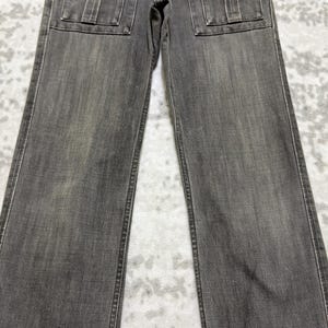 May include: A pair of gray denim jeans with two square pockets on the front. The jeans have a straight leg cut and a faded appearance. The stitching is visible along the seams and pockets.