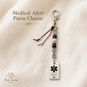 May include: A medical alert purse charm with a silver clasp, brown leather cord, and decorative beads. The charm includes a rectangular tag with the medical alert symbol and the words "MEDICAL ALERT". The text "Medical Alert Purse Charm" is also in the image.