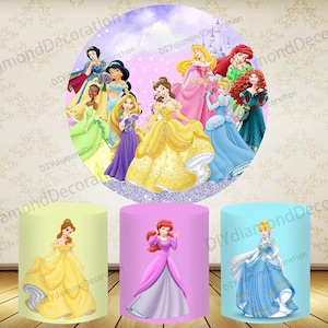May include: A circular backdrop and three cylindrical stands featuring Disney princesses. The backdrop showcases multiple princesses against a purple sky with a castle. The stands display Belle, Ariel, and Cinderella.