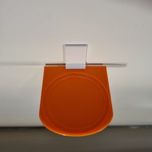 May include: Orange plastic wall mount with a round, recessed area. The mount is attached to a white wall.