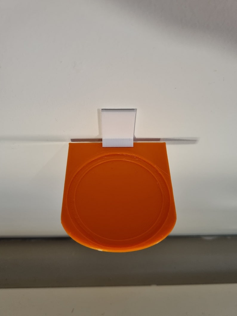 May include: Orange plastic wall mount with a round, recessed area. The mount is attached to a white wall.