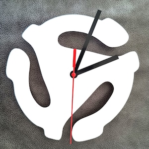 May include: White vinyl record clock with black and red hands. The clock is shaped like a record with a centre hole and three grooves.