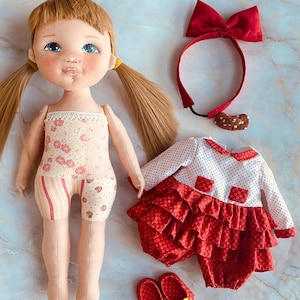 Puede incluir: Una muñeca hecha a mano con cabello rubio, ojos azules y un vestido floral rosa y blanco. La muñeca lleva una diadema roja con un lazo y zapatos rojos con flores amarillas. La muñeca también lleva un vestido rojo con lunares blancos y una falda con volantes.