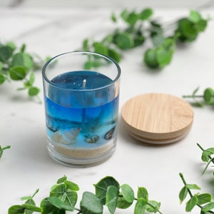 Handmade nautical blue gel candle with cotton wick and with sand and shells with beach bum scent  in a glass cup