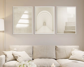 May include: A set of three vertical wall art prints in white frames. The left print shows a textured beige surface with light shadows. The center print depicts a series of repeating white arches. The right print features a staircase in neutral tones.