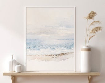 May include: A watercolor painting of a seascape with blue water, white waves, and a sandy beach. The painting is framed in a white frame and is hanging on a white wall.