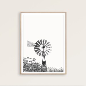 May include: Black and white photograph of a windmill with the text "The Aermotor Chicago" on the side. The windmill is surrounded by tall grass.