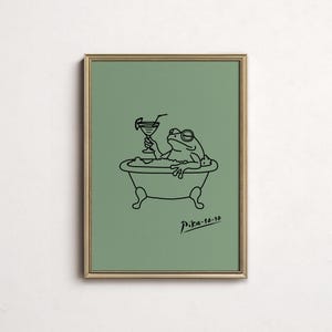 May include: A framed art print featuring a whimsical illustration of a frog in a bathtub, holding a cocktail. The black line art is set against a muted green background. The print is signed "Pika-50-30".