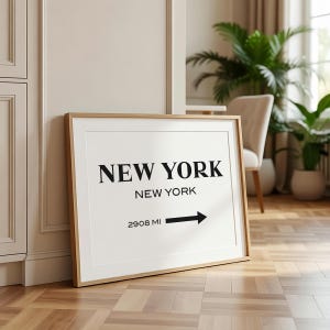 May include: A rectangular framed print featuring the text NEW YORK in large black capital letters, followed by NEW YORK in smaller text, and the text 2908 MI with a black arrow pointing to the right, all set against a white background.