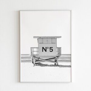 Puede incluir: Fotograf&iacute;a en blanco y negro de una caseta de salvavidas en una playa. La caseta est&aacute; numerada "N&deg; 5".