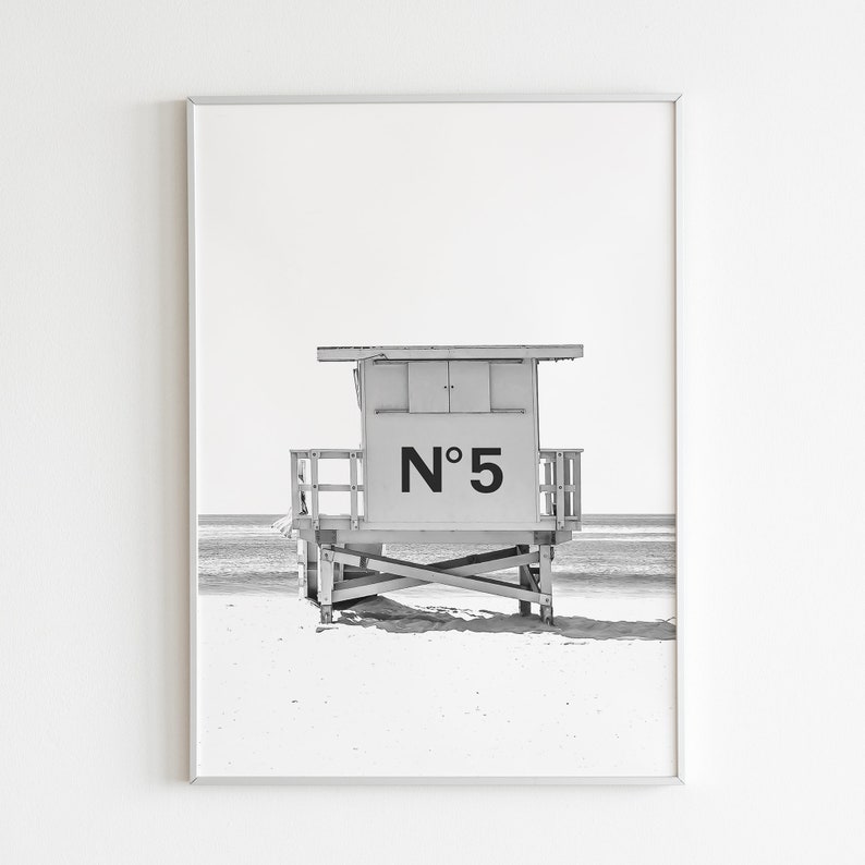 Puede incluir: Fotograf&iacute;a en blanco y negro de una caseta de salvavidas en una playa. La caseta est&aacute; numerada "N&deg; 5".