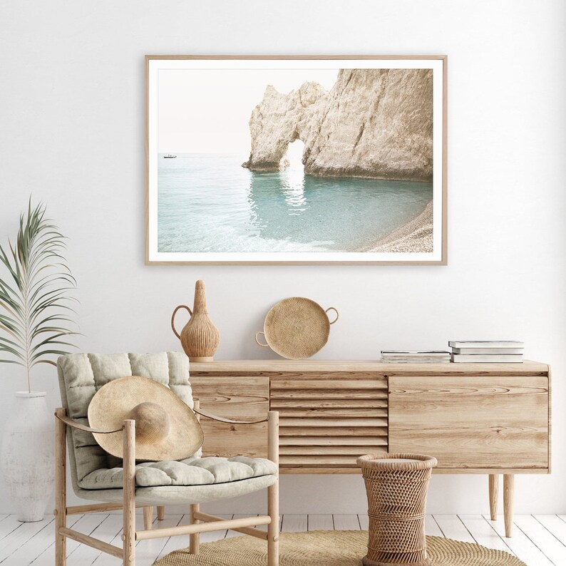 Puede incluir: Una fotograf&iacute;a enmarcada de un arco de roca natural en una playa con agua turquesa. El arco est&aacute; hecho de roca blanca y el agua est&aacute; tranquila y clara. Se puede ver un peque&ntilde;o barco en la distancia.