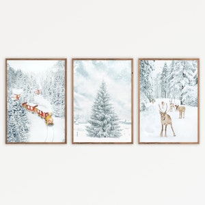 May include: A set of three framed wall art prints featuring winter scenes. The first shows a red train in a snowy forest, the second a snow-covered pine tree, and the third a group of reindeer standing in a white, frost-covered landscape.