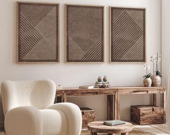 May include: Three framed wall art pieces with geometric designs in shades of brown and beige. The artwork hangs above a wooden console table with decorative items. A cream-colored armchair and a round coffee table complete the room's decor.