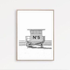 Puede incluir: Fotograf&iacute;a en blanco y negro de una caseta de salvavidas en una playa. La caseta est&aacute; numerada "N&deg; 5".