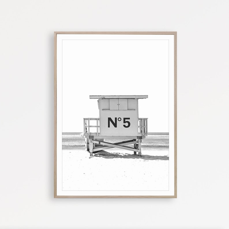 Puede incluir: Fotograf&iacute;a en blanco y negro de una caseta de salvavidas en una playa. La caseta est&aacute; numerada "N&deg; 5".