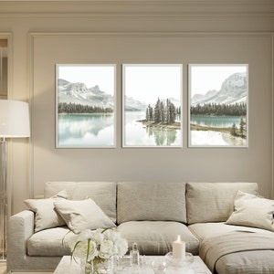 May include: Three framed landscape photographs of a lake with mountains in the background. The lake is surrounded by trees and the mountains are covered in snow. The photos are in a minimalist style with a muted color palette.