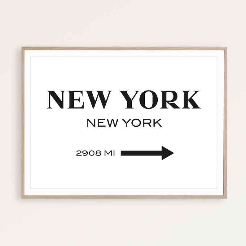 May include: A framed wall art print featuring the text NEW YORK in large bold serif font, followed by NEW YORK in smaller sans-serif font, and the text 2908 MI with a black arrow pointing to the right. The frame is a light-colored wood finish.