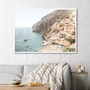 May include: A panoramic view of a coastal town built into a cliffside. The town is a mix of white and yellow buildings with red tile roofs. The town is situated on a rocky coastline with a clear blue ocean in the foreground. There are several boats in the water.